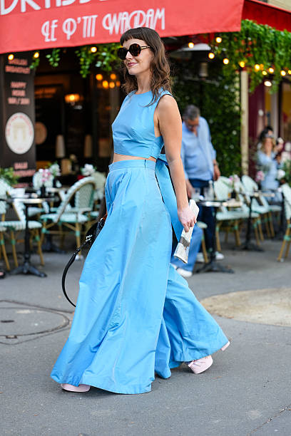 Guest wears a sleeveless, light blue crop top paired with matching high-waisted, wide-leg trousers. The ensemble appears to be made of a lightweight...