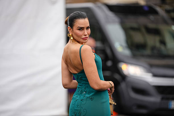 Guest wears a teal dress with thin straps and intricate floral embroidery detailing on the back. The dress features a fitted silhouette. Large gold...