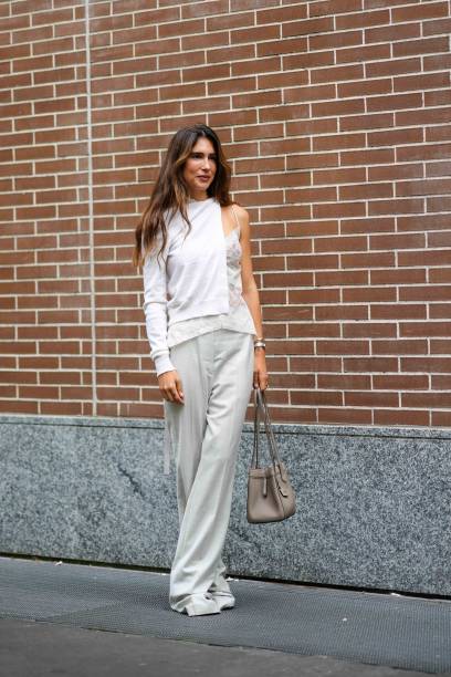 Guest wears a white cardigan, a white lace strappy lingerie top, white long pants, a light brown ba, outside Fendi, during the Milan Fashion Week -...
