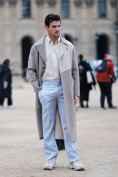 Guest wears a white shirt, a grey and beige trench coat, blue pants, white sneakers, outside Off-White, during the Womenswear Fall/Winter 2024/2025...