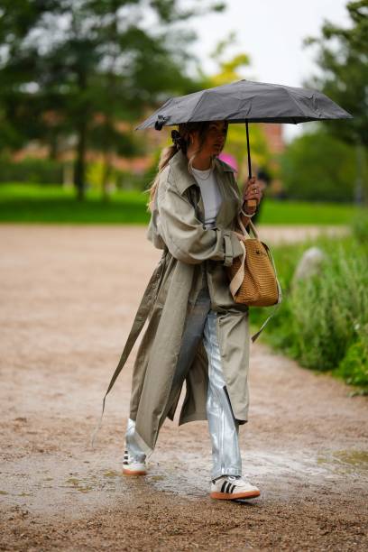 Guest wears a white t-shirt, a pale khaki long trench coat, a camel braided wickers handbag from Marni, silver blue shiny coated canvas large...