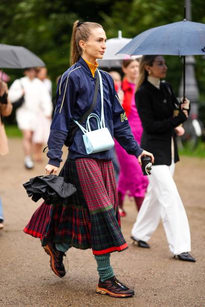 Guest wears a yellow turtleneck pullover, a navy blue with yellow embroidered pattern zipper sport sweater, a pale blue matte leather crossbody bag...