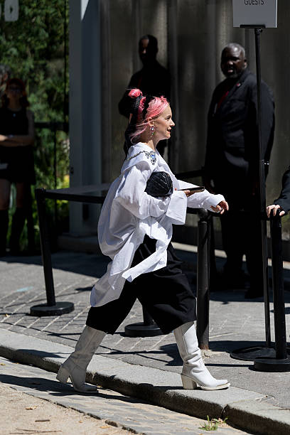 Guest wears an oversized white button-up shirt adorned with jeweled brooches and a silver chain detail, black wide-leg cropped trousers, white...
