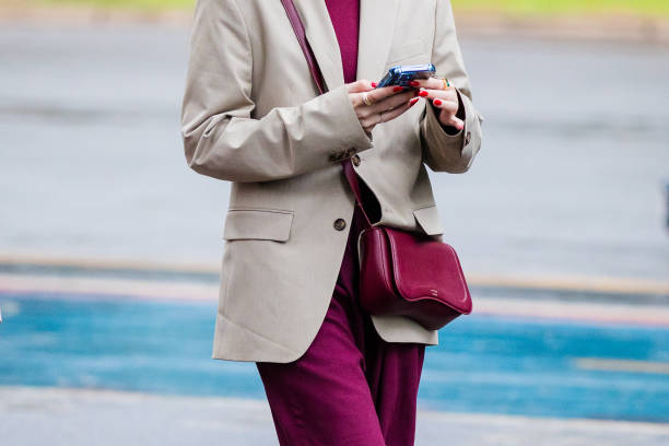 Guest wears beige blazer, burgundy top, matching burgundy pants, burgundy crossbody bag, red nails, gold rings at Sao Paulo Fashion Week 2024 N58 -...