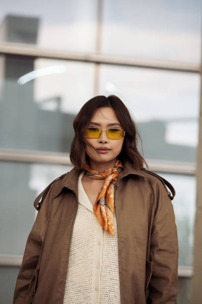 Guest wears beige top, neck scarf, yellow sunglasses and a brown leather jacket on day 1 of Visa Fashion Week Almaty 2024 on May 01, 2024 in Almaty,...