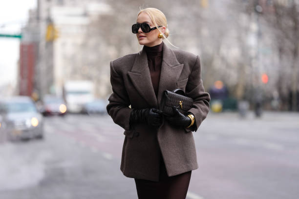 Guest wears black Altuzarra sunglasses, gold earrings, deep dark brown turtleneck long sleeve form fitting midi dress, dark brown oversized double...