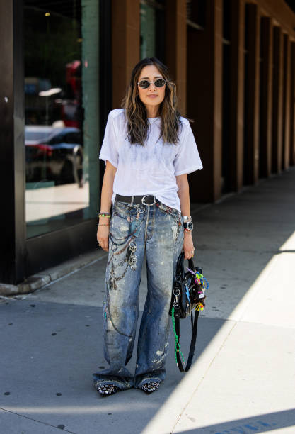 Guest wears black Balenciaga bag, denim jeans with print, white shirt outside Brandon Maxwell during New York Fashion Week on September 06, 2024 in...