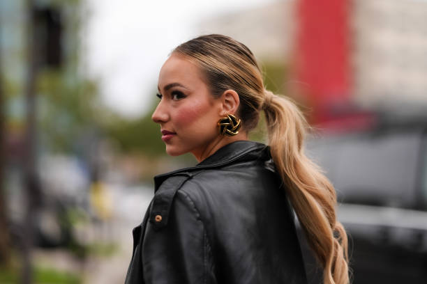 Guest wears black gold earrings, shiny black leather trench coat, outside Valentino, during the Paris Fashion week Spring/Summer 2025 on September...
