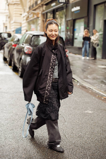 Guest wears black jeans, balck skirt, grey top and black jacket and blue mini bag outside The Cecilie Bahnsen show during Womenswear Spring/Summer...