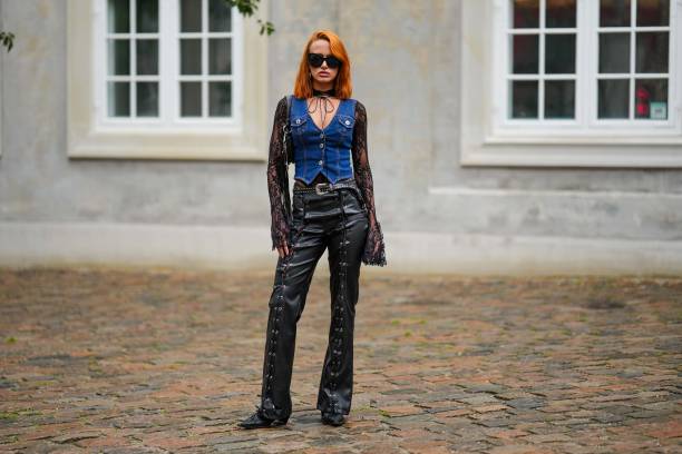 Guest wears black large sunglasses, a black embroidered lace flower pattern long sleeves t-shirt, a navy blue denim sleeveless cargo pants, a black...