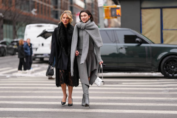 Guest wears black oversized Michael Kors coat, black faux fur scarf, black sheer mesh floral lace midi Michael Kors skirt, shiny black Michael Kors...