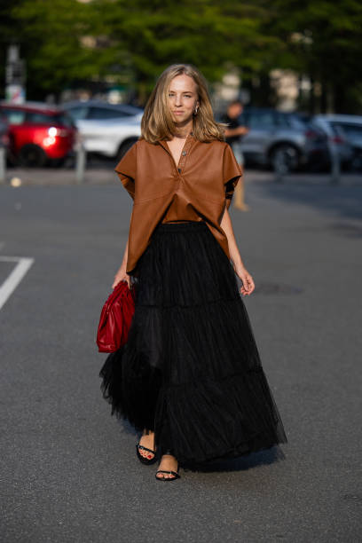 Guest wears black skirt, brown leather shirt, red bag outside Baum & Pferdgarten during day three of the Copenhagen Fashion Week SS25 on August 07,...