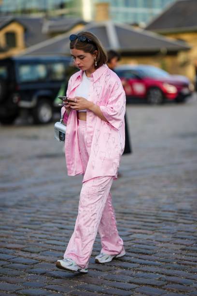 Guest wears black sunglasses, a white tank-top, a pale pink embroidered crystals heart pattern oversized shirt, matching pale pink embroidered...