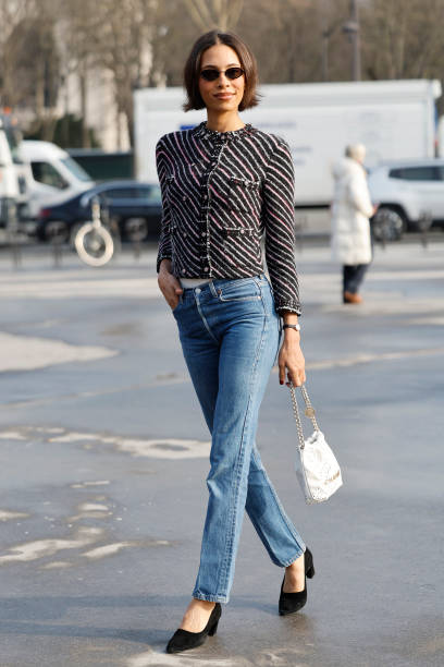 Guest wears black white and red striped jacket, blue jeans, white Chanel bag, outside Chanel, during the Womenswear Fall/Winter 2025/2026 as part of...