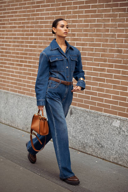 Guest wears blue jeans, a blue denim shirt, and a brown leather bag outside Fendi during the Milan Fashion Week - Womenswear Fall/Winter 2024-2025 on...