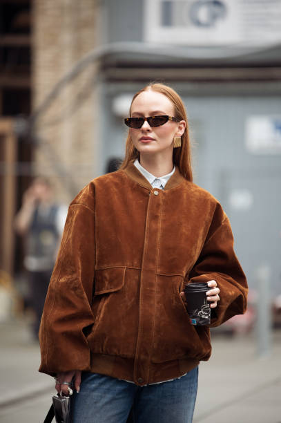 Guest wears blue jeans, brown suede jacket and black bag outside the Herskind fashion show during the Copenhagen Fashion Week Autumn/Winter 2025 on...
