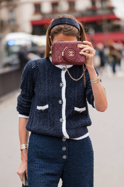 Guest wears blue tweed chanel cardigan, blue tweed pants, burgundy Chanel bag, outside Chanel, during the Womenswear Fall/Winter 2024/2025 as part of...