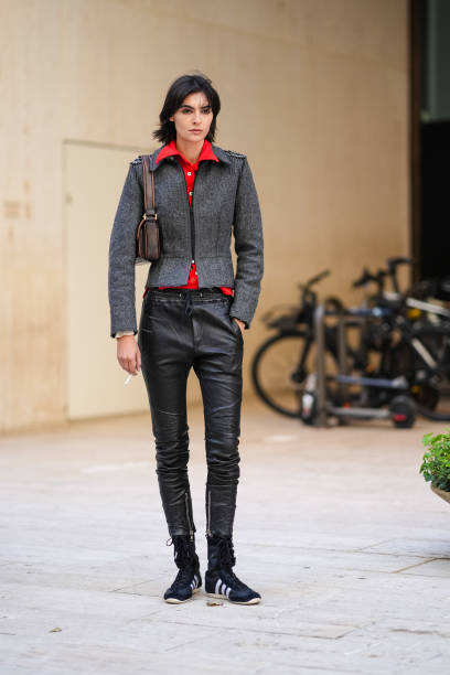 Guest wears bright red buttoned up long sleeve shirt, dark gray tailored jacket, dark brown leather bag, shiny black skinny leather jeans, black gray...