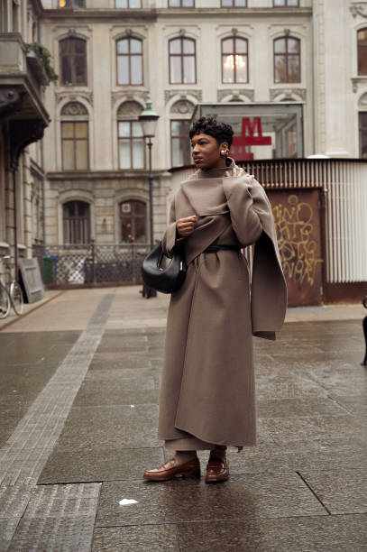 Guest wears brown coat, brown shoes, and a black bag outside Aeron during the Copenhagen Fashion Week AW24 on January 30, 2024 in Copenhagen, Denmark.