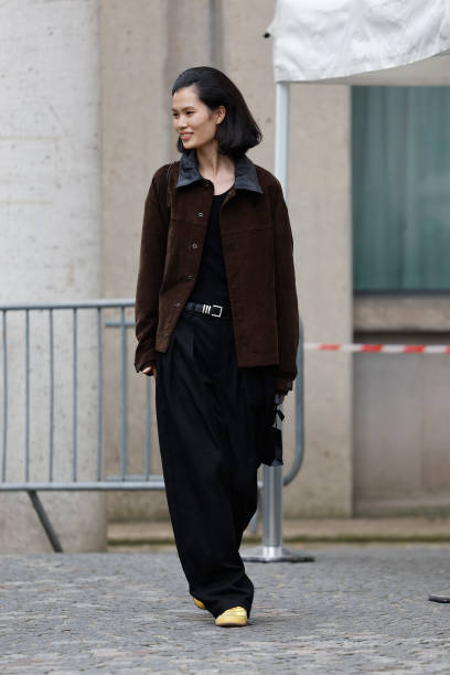 Guest wears brown jacket with leather collar, black trousers, yellow sneakers, outside Miu Miu, during the Womenswear Fall/Winter 2025/2026 as part...