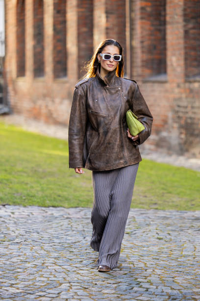 Guest wears brown leather jacket, grey pleated skirt outside Herskind during the Copenhagen Fashion Week AW24 on January 31, 2024 in Copenhagen,...