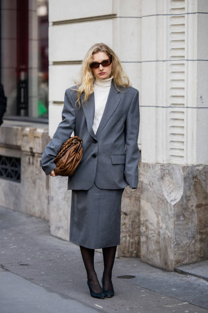 Guest wears brown Miu Miu bag, grey suit outside Magda Butrym presentation during the Womenswear Fall/Winter 2025/2026 as part of Paris Fashion Week...