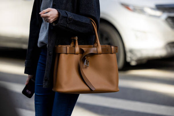 Guest wears brown Prada bag outside Calvin Klein on February 07, 2025 in New York City.