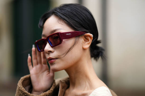 Guest wears burgundy squared sunglasses from Prada, a beige heart-neck / cut-out chest / short tube jumpsuit, a brown shiny leather and sheep fur...