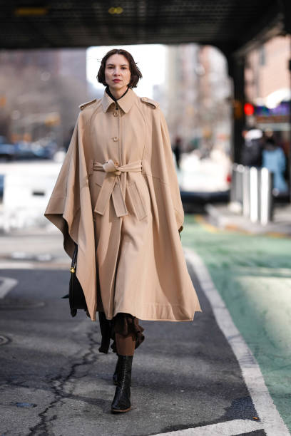 Guest wears dark brow belted trench cape, dark brown midi skirt, dark brown tights, shiny black pointed toe heel leather shoes, shiny black leather...