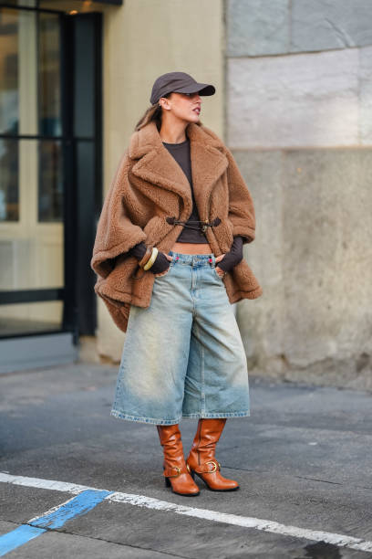 Guest wears dark brown Baseball hat, dark brown long sleeve shirt, light brown teddy bear oversized Max Mara coat, washed denim jean jorts, light...