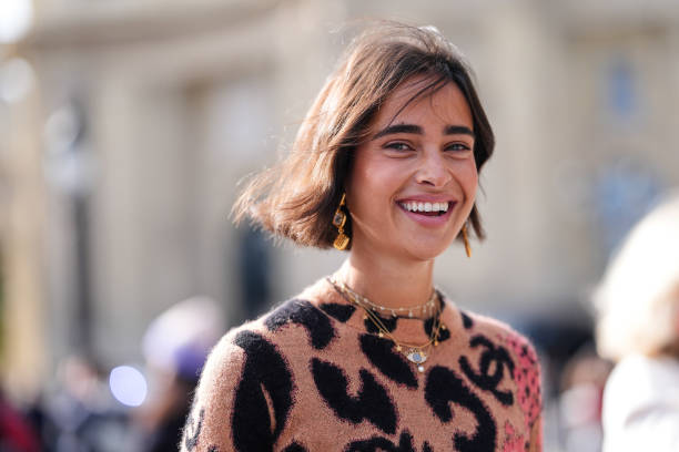 Guest wears dark brown black leopard pattern/print red floral pattern/print sweater, outside Chanel, during the Paris Fashion Week Spring/Summer 2025...