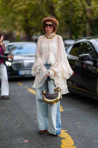 Guest wears dark brown fluffy headband, gold necklace, dark brown sunglasses, white sheer mesh high neck flowy long sleeve Chloe shirt, dark gray...