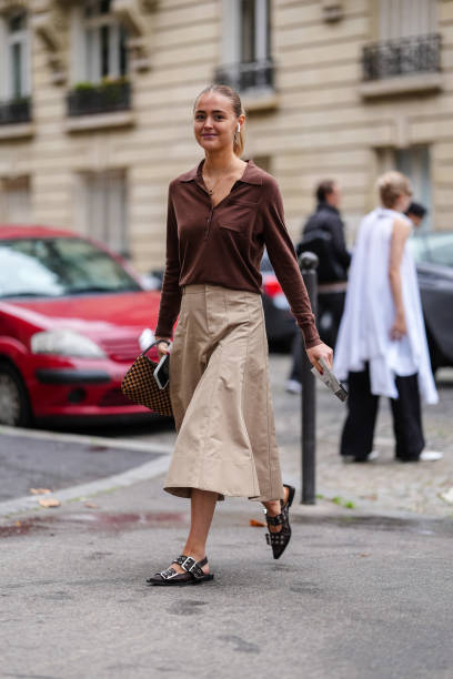 Guest wears dark brown long sleeve shirt, light brown midi skirt, black belted slingback Ganni leather shoes, dark brown pattern bag, outside Stella...