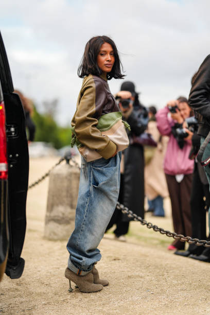Guest wears dark green dark brown leather jacket, light green light gray clutch leather bag, washed denim jean baggy pants, light gray brown fluffy...