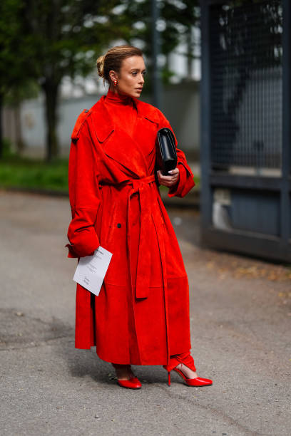 Guest wears gold earrings, bright red turtleneck long sleeve Ferragamo, bright red suede Ferragamo trench coat, bright red tight Ferragamo pants,...