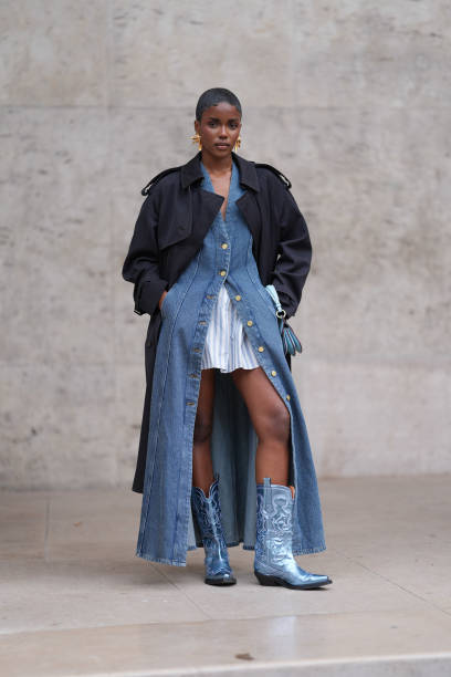Guest wears, gold earrings, dark blue trench coat, navy blue denim jean unbuttoned midi dress, white blue striped buttoned long sleeve oversized...