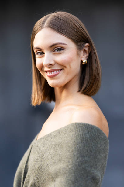 Guest wears gold hoop earrings and a dove grey knitted sweater outside Philosophy show during the Milan Fashion Week Menswear Spring/Summer 2025 on...