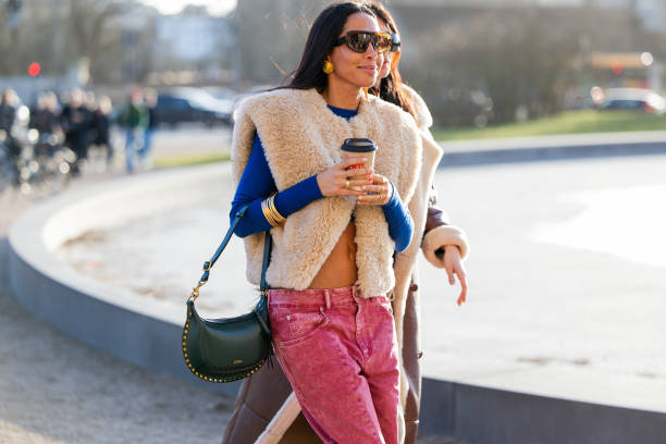 Guest wears green bag, vest, red pants outside Marimekko during the Copenhagen Fashion Week AW24 on February 01, 2024 in Copenhagen, Denmark.