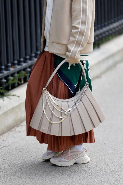 Guest wears green Lacoste printed long top, cream cardigan, beige Lacoste jacket, brown pleated maxi skirt, beige Lacoste bag, beige Lacoste...