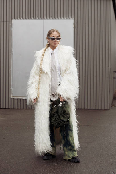 Guest wears green pants, a white shirt, a grey tie with cut out heart, and an army green bag outside Vain during the Copenhagen Fashion Week AW24 on...