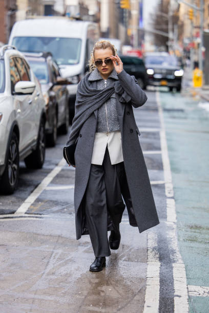 Guest wears grey coat, zipper, pants outside Michael Kors on February 13, 2024 in New York City.