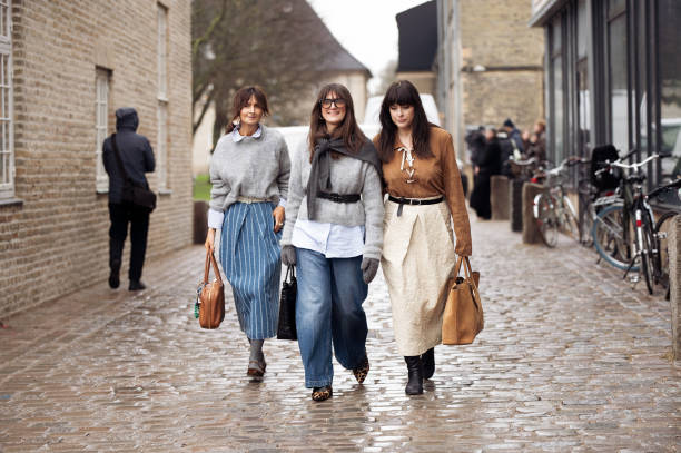 Guest wears grey sweater, blue denim skirt, brown bag and a guest wears grey sweater with black belt, blue jeans and a guest wears pale yellow skirt,...