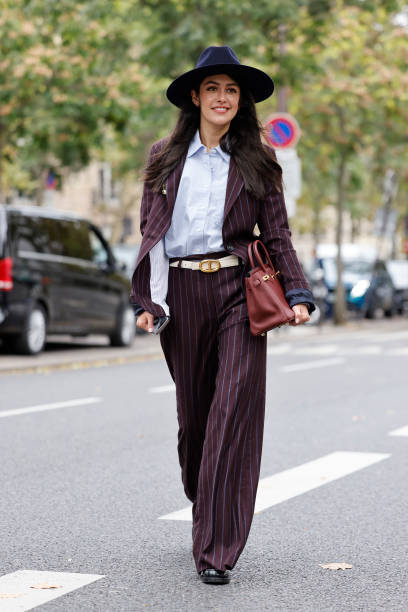 Guest wears light blue shirt, burgundy striped suit, blue hat, burgundy Hermes bag, outside Shiatzy Chen, during Womenswear Spring/Summer 2025 as...