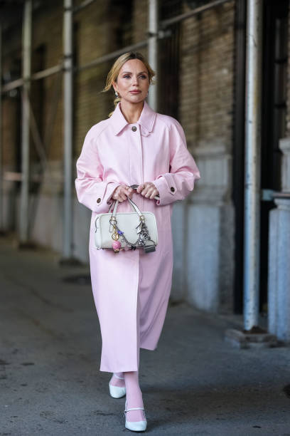 Guest wears light pink Coach leather wind coat, white leather bag, bag charms, white tights, white mary jane heels, outside Coach, during the New...