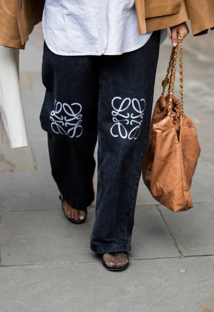 Guest wears Loewe jeans, Chanel bag in brown outside Simone Rocha during London Fashion Week September 2024 on September 15, 2024 in London, England.