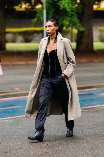 Guest wears long beige coat, black corset top, black pants, black ankle boots, braided hairstyle at Sao Paulo Fashion Week 2024 N58 - Street Style at...