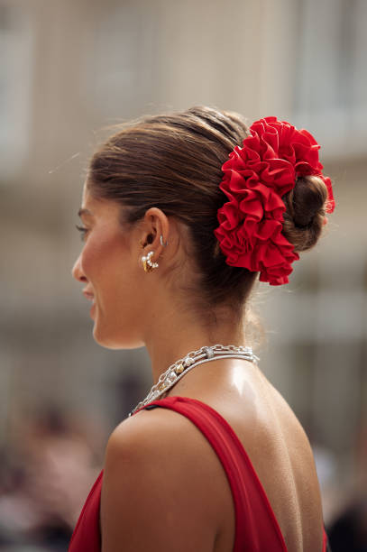 Guest wears long red sheer maxi dress, black bag, silver layered necklaces, red scrunchy for hair is seen outside the Gestuz show during day four of...