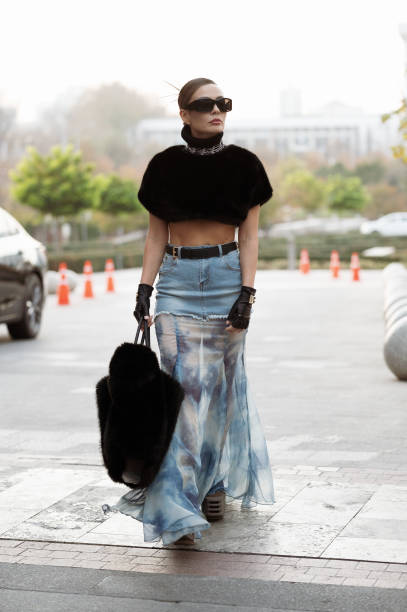 Guest wears long skirt part blue denim, part white and blue silk with a black belt, black leather gloves from Dolce & Gabbana, black big fur bag,...