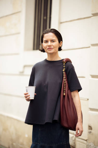 Guest wears navy blue T-shirt, dark blue denim skirt, burgundy bag outside the Loewe presentation during the Womenswear Fall/Winter 2025/2026 as part...