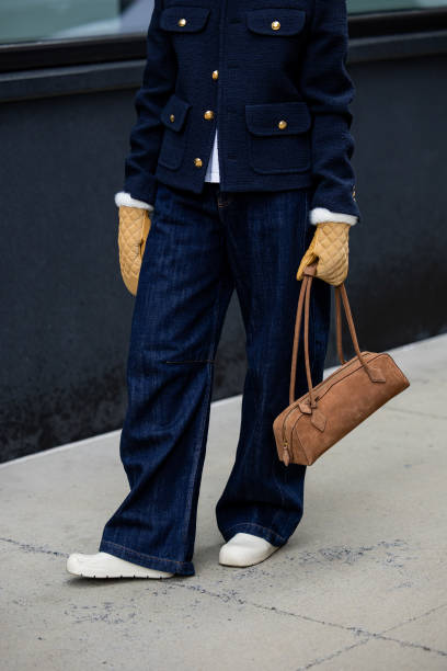 Guest wears navy jacket, jeans, Alaia bag in brown, beige gloves outside Ulla Johnson during New York Fashion Week on February 09, 2025 in New York...